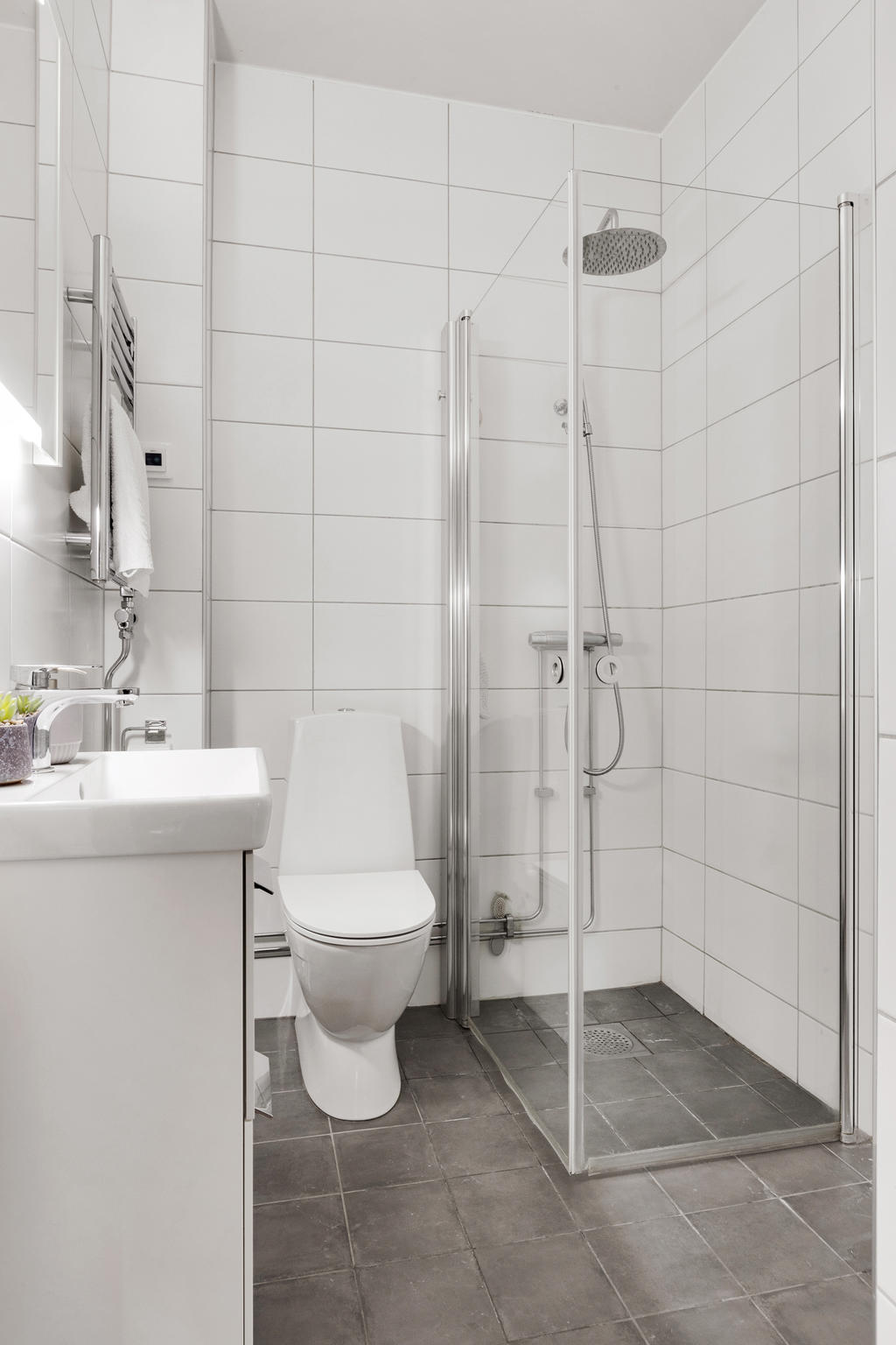 Renoverat och helkaklat badrum utrustat med dusch, handdukstork och WC