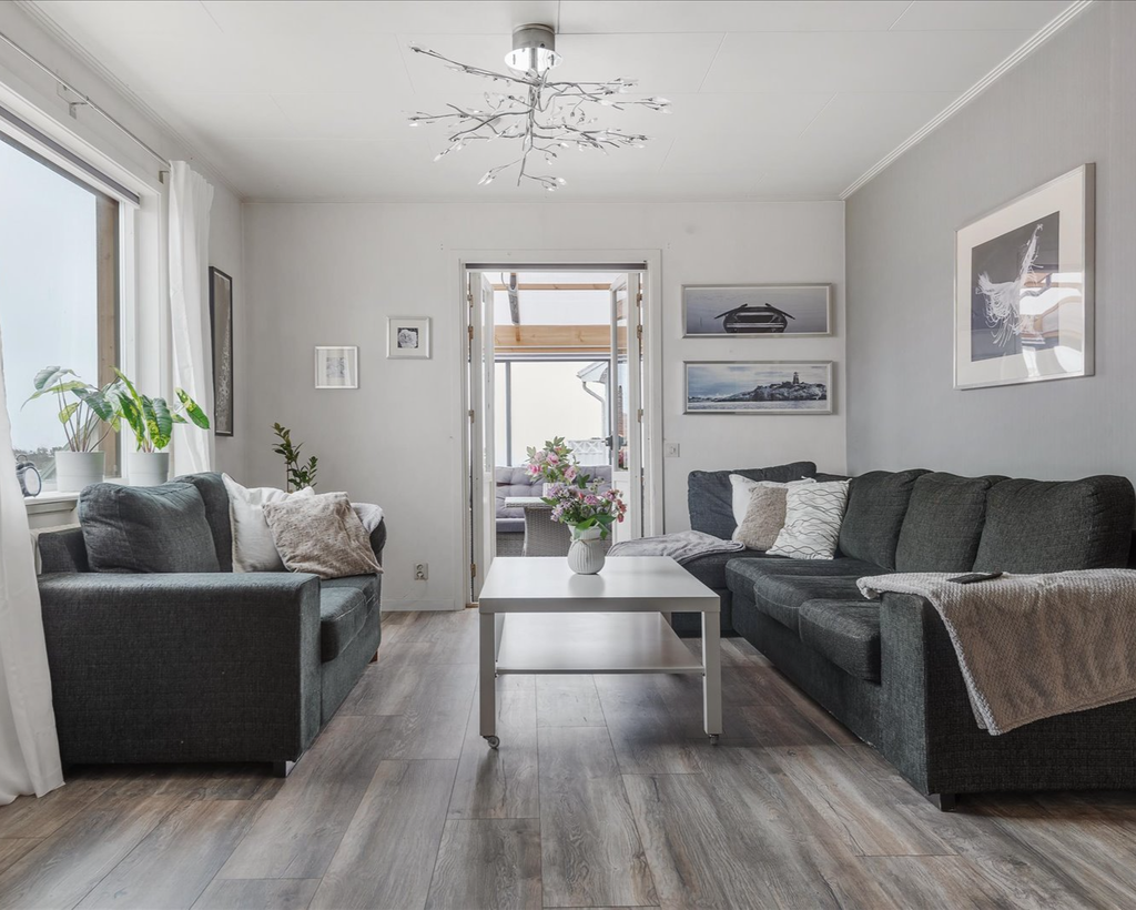 Vardagsrum med öppna dubbeldörrar mot inglasat uterum 