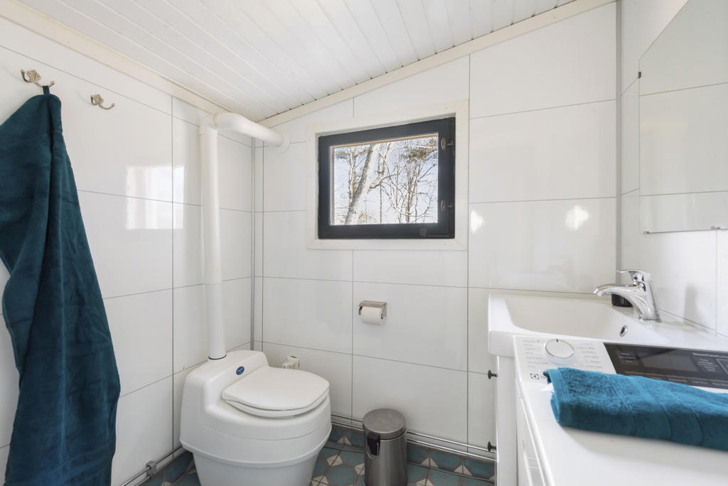 Toalettutrymme med en separett, handfat och tvättmaskin.