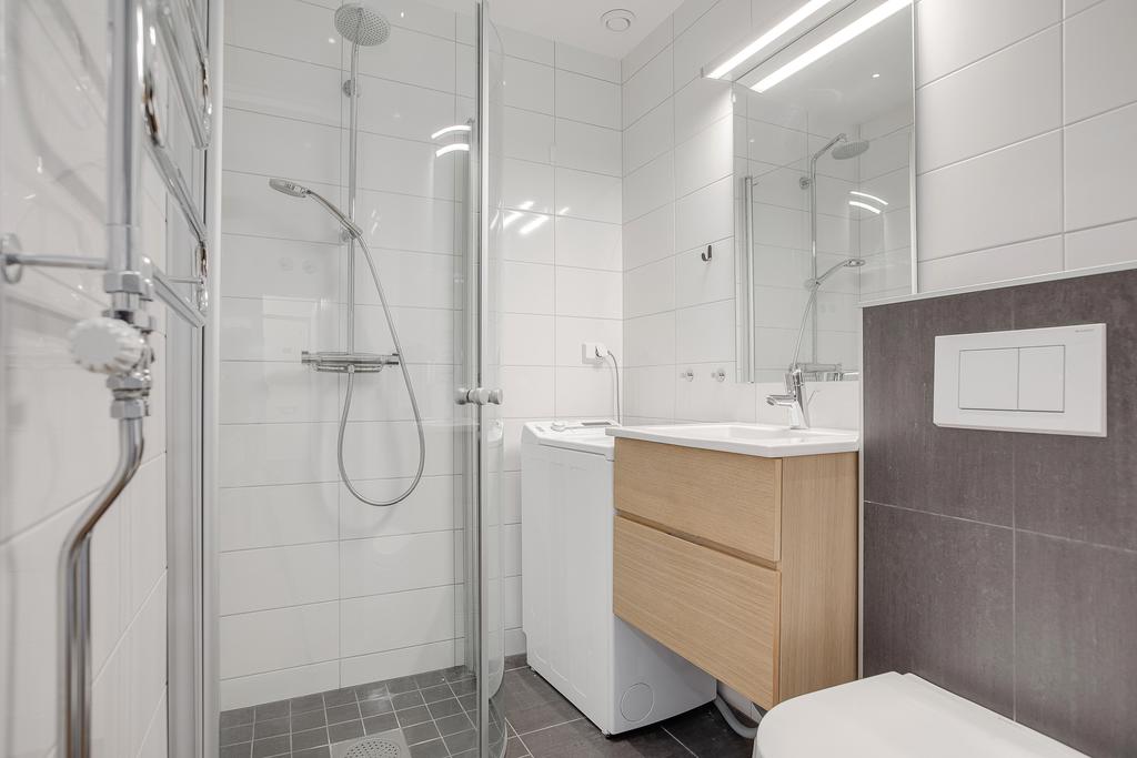 Helkaklat badrum med kommod, handdukstork och tvättmaskin