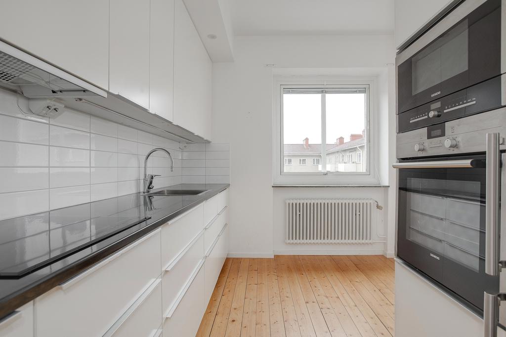 Kök med diskmaskin och integrerade vitvaror i rostfritt stål samt häll