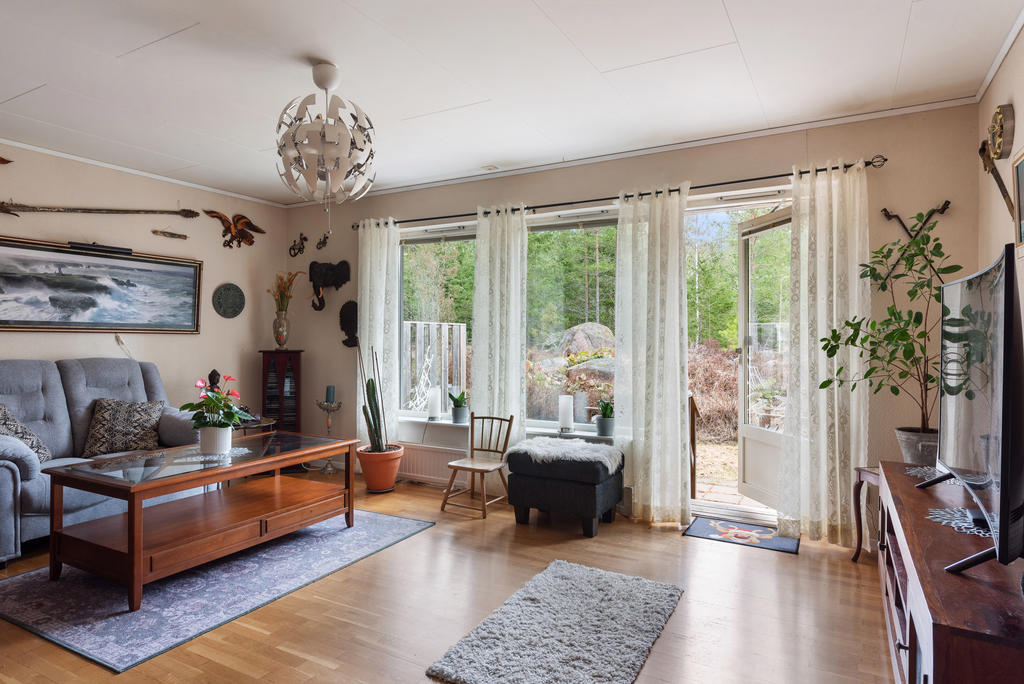 Vardagsrum med ekparkett och utgång till betongstensatt uteplats
