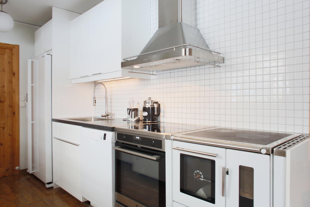 Kök med vedspis och ny spis intill från 2024