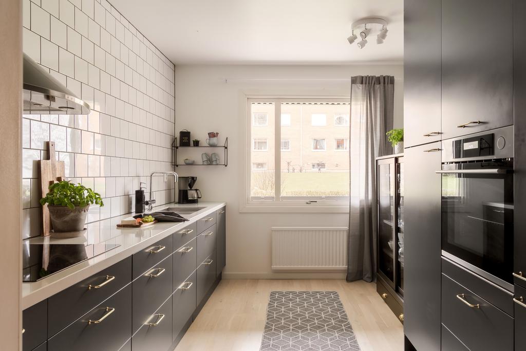 De mörkare skåpsluckorna möter ljusa kakelväggar och skapar en snygg kontrast, medan kompositskivan ger ett exklusivt intryck.