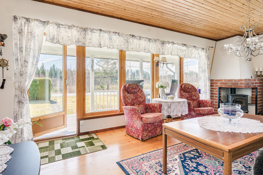 Välkommen in till ett hemtrevligt vardagsrum med fint parkettgolv, kamin samt stora glaspartier som ger mycket ljusinsläpp.