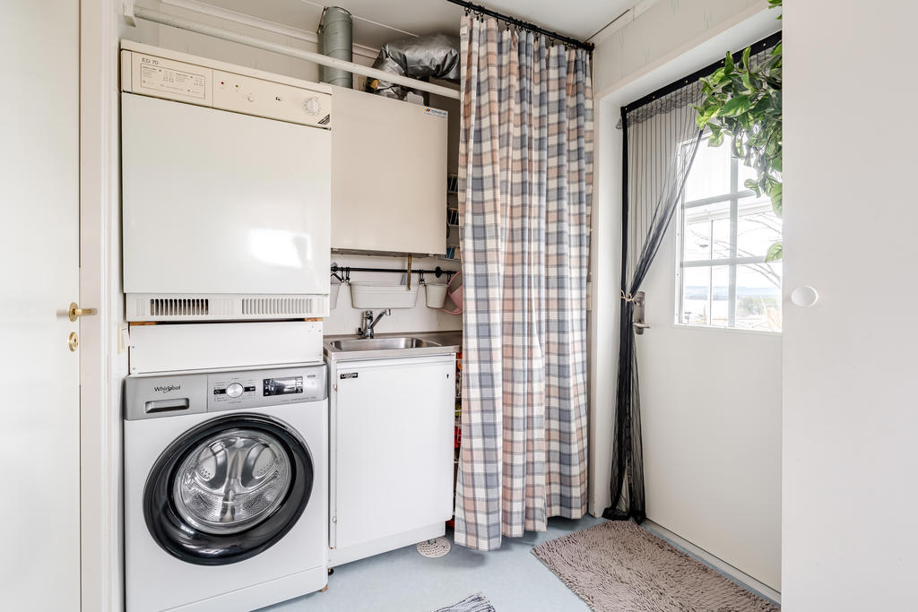 Tvättmaskin, torktumlare och tvättbänk samt ventilation och utgång.
