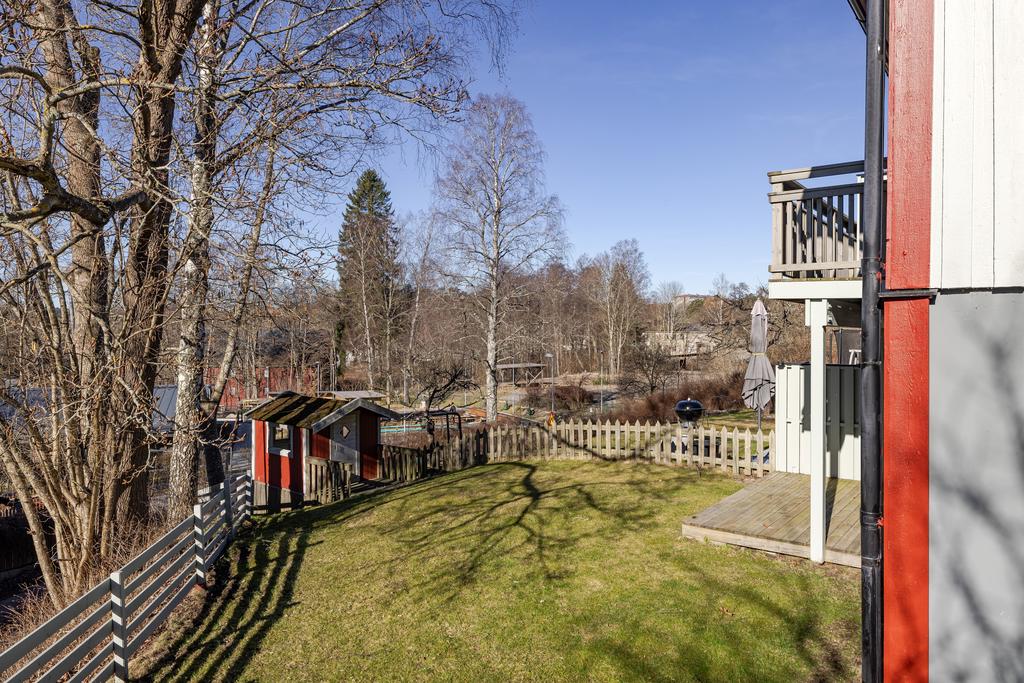 Trädgård med altan, gräsytor och en lekstuga. Inramad med nytt staket. 