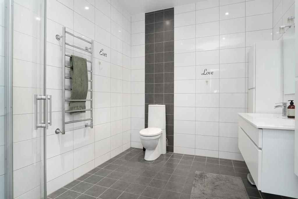 Badrummet går i vitt och grått med dusch. Inredning från Kvikk