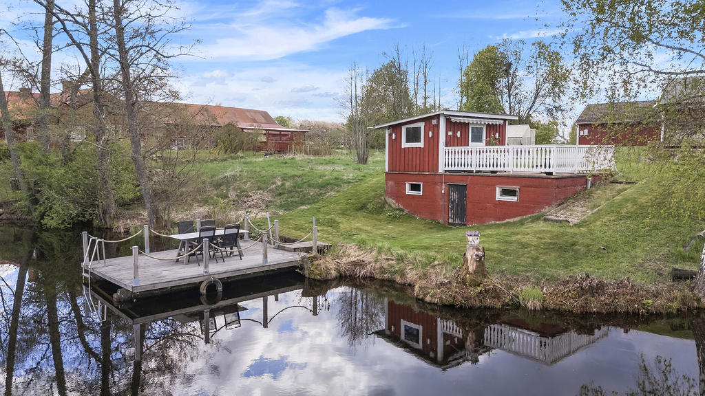 Uthus med förrådsutrymmen samt uteplats intill bryggan