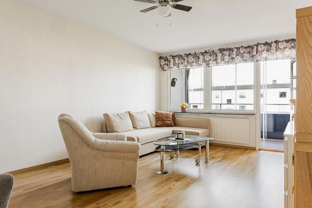 Vardagsrum med ljusa väggar och parkettgolv