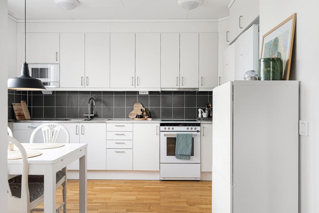 Stilrent kök med luckor och vitvaror i vitt