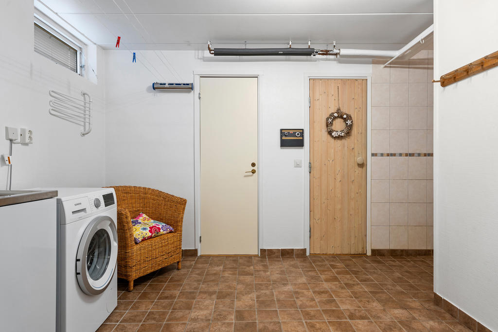 Stor tvättstuga som angränsar till dusch, bastu samt ett förråd.