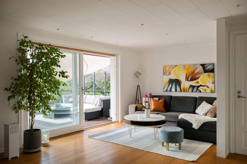 Det generösa allrummet på entréplan blir en naturlig samlingsplats för både avkoppling och umgänge. Här flödar ljuset in från panoramadörrarna och skapar en varm och inbjudande känsla med fin kontakt mot trädgården och uteplatsen.