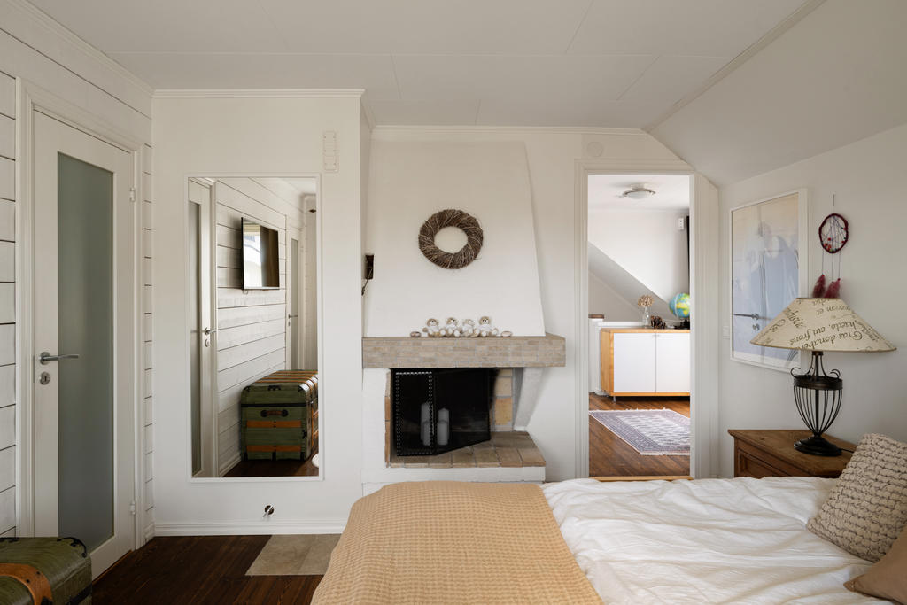 Master Bedroom med inbyggd klädkammare och en vacker öppen spis som skapar en varm och exklusiv hotellkänsla. Ett rofyllt och elegant rum där komfort och atmosfär möts på bästa sätt.