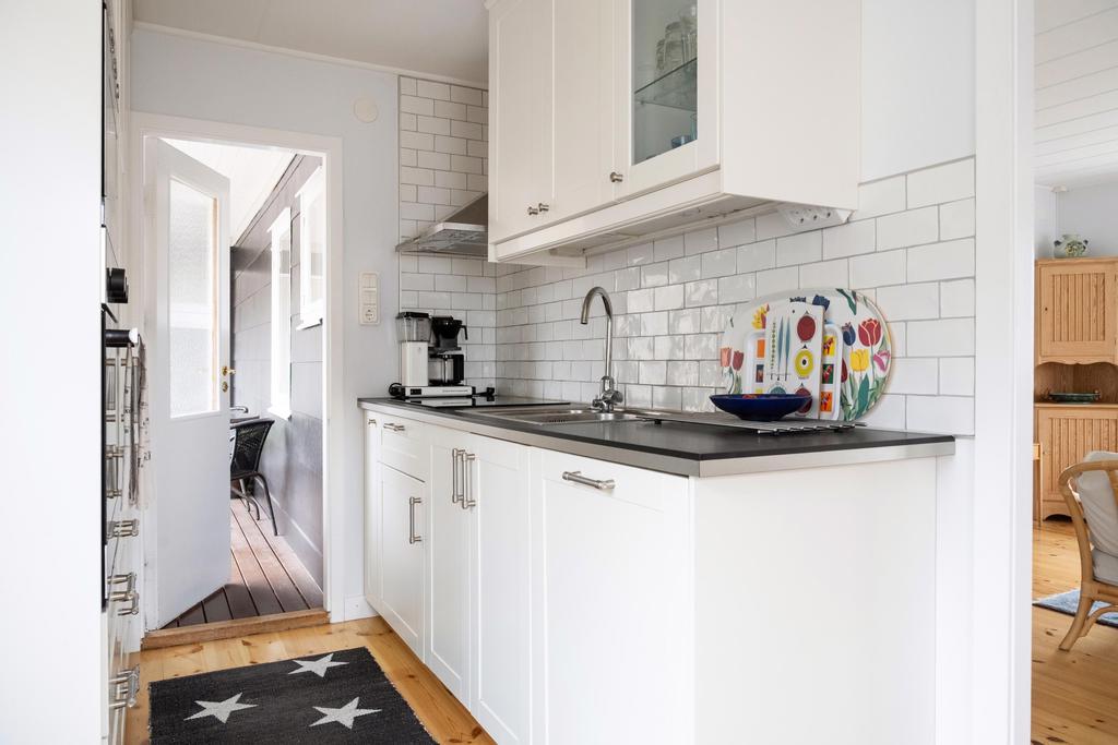 Stilrent kök från 2014 med modern spishäll, diskmaskin samt kyl och frys. Genomtänkt förvaring med välplanerade skåp och luckor skapar en funktionell och lättarbetad matlagningsmiljö.