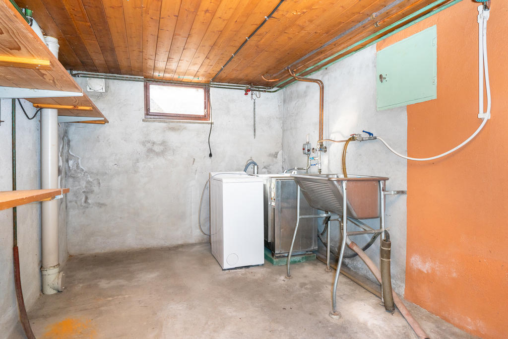 Tvättrum med tvättmaskin. Äldre tvättmaskin gjuten i grunden.