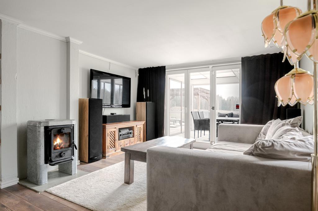 Vardagsrum med täljstenskamin och utgång till inglasad altan