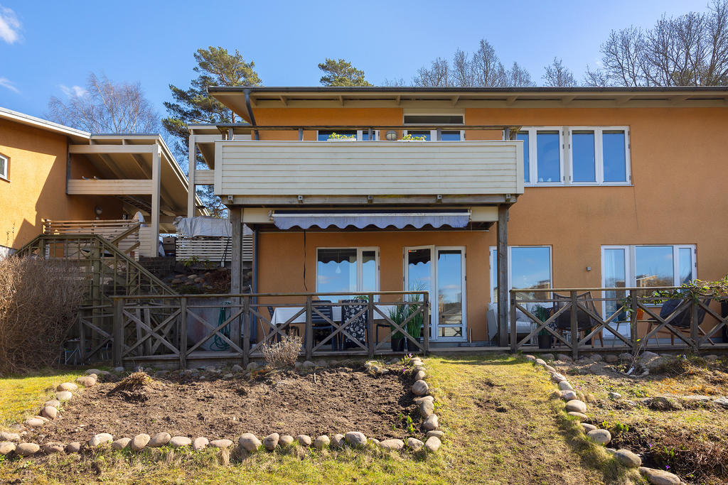 Bostadens baksida, med trappa från framsidan ner till bostadens altan och trädgård