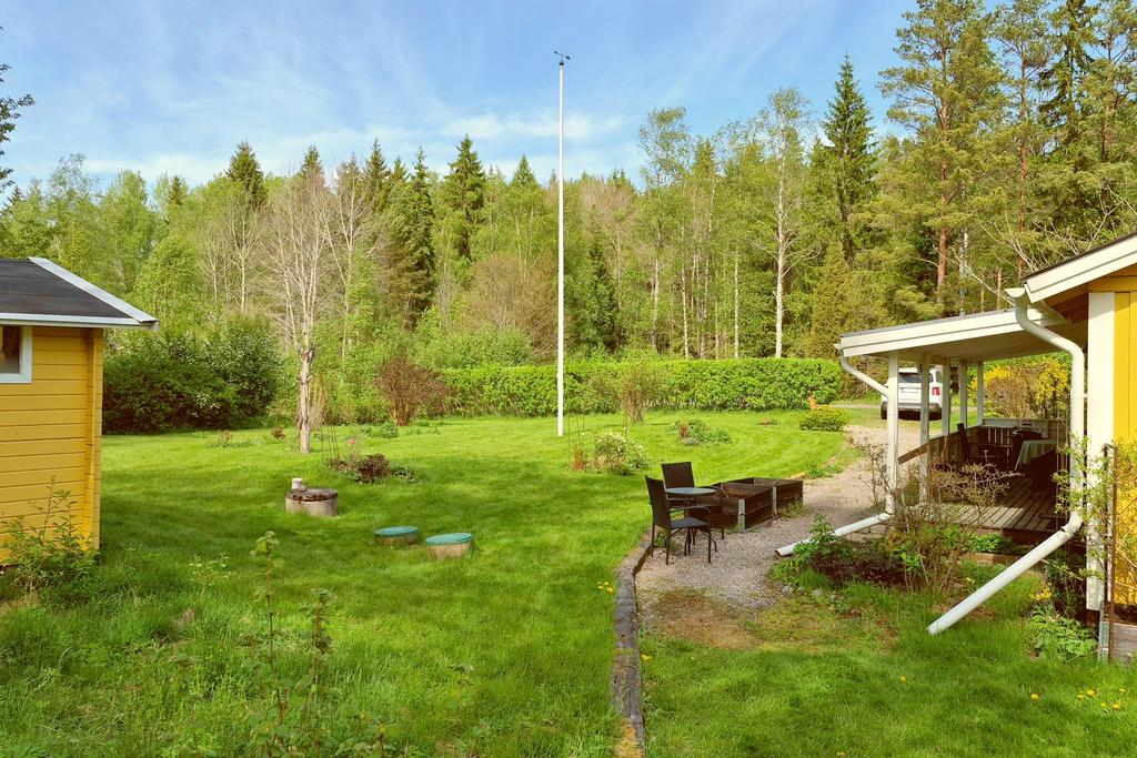 Stor gräsmatta framför huset och häck mot den lilla grusvägen