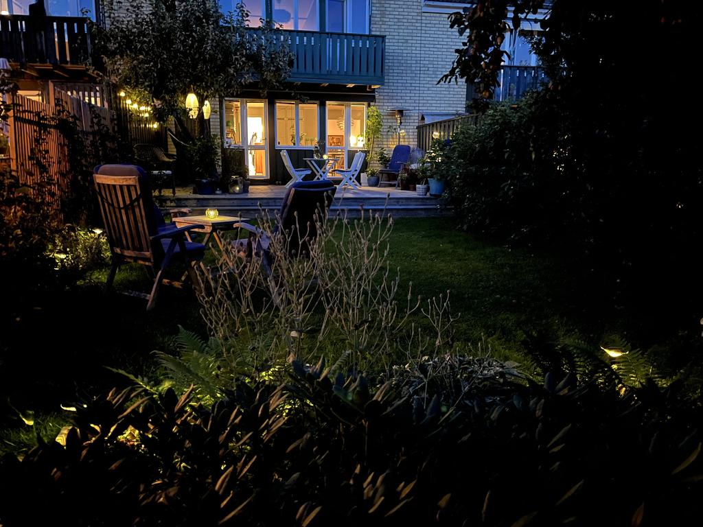 Upplyst trädgård och uteplats intill kök i skymning på Bovägen 23