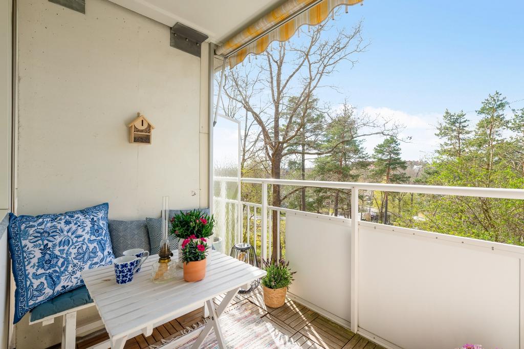 Möblerbar balkong med markis och fri utsikt mot grönska och Skärsätra villabebyggelse
