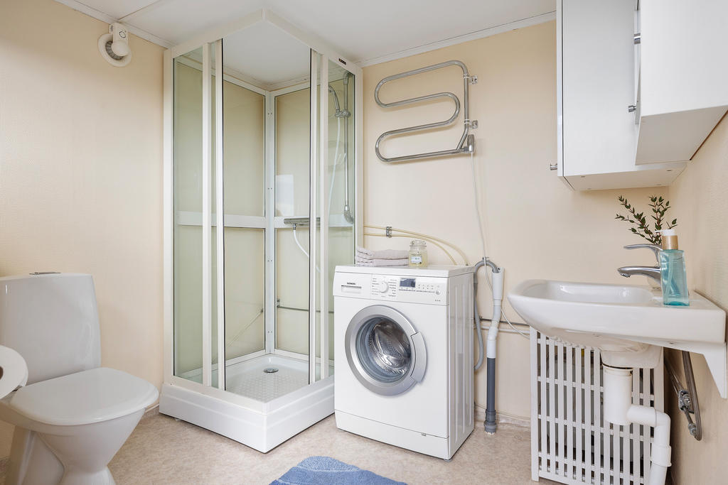 Badrum utrustad med toalett, duschkabin, handfat och tvättmaskin i komplementhuset