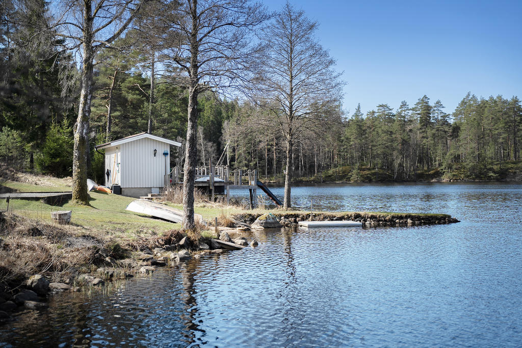 Stranden med ett litet bostadshus med altan över vattnet.  
