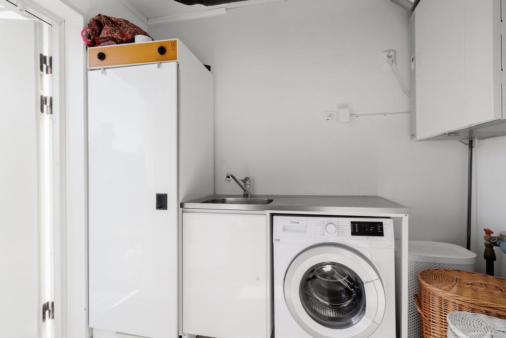 Groventré/Tvättstuga med plastmatta och målade väggar, utrustat med fjärrvärmeväxlare -17, TFX-aggregat -10, tvättmaskin, torkskåp och tvättbänk med ho samt utgång till trädgård