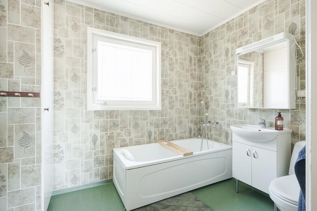 Badrum på entréplan. Förvaringsskåp till vänster, badkar, toalett samt handfat och förvaring bakom spegelförsedda dörrar