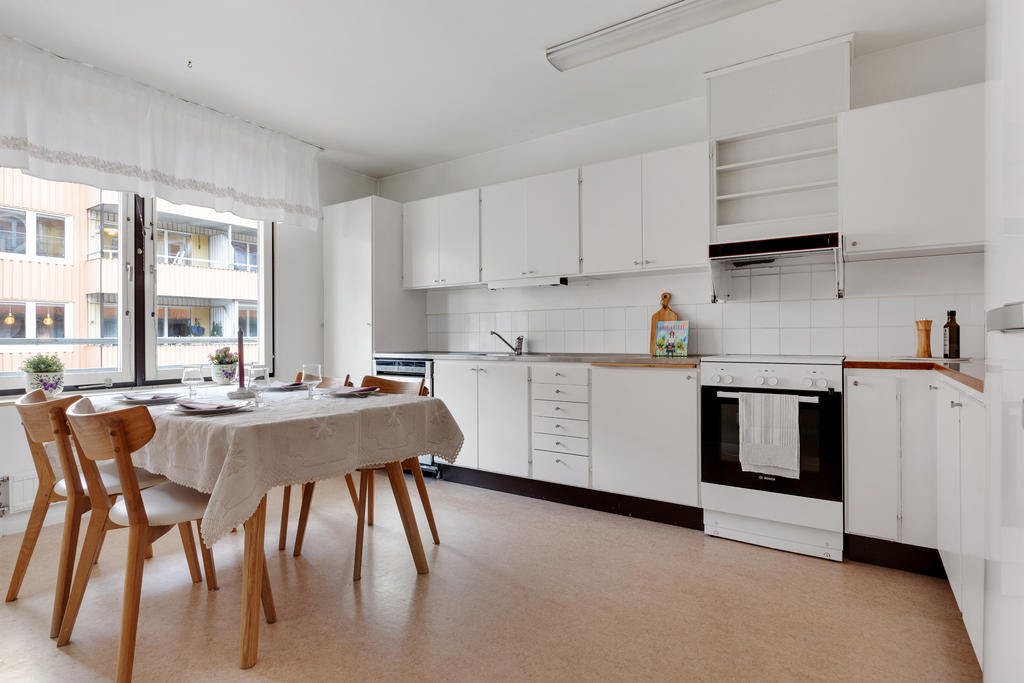 Kök i vitt med goda förvaringsmöjligheter och plats för ett stort matbord vid fönstret