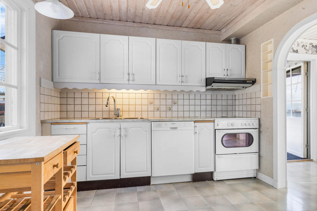 Kök med fläkt, spis och diskmaskin. 