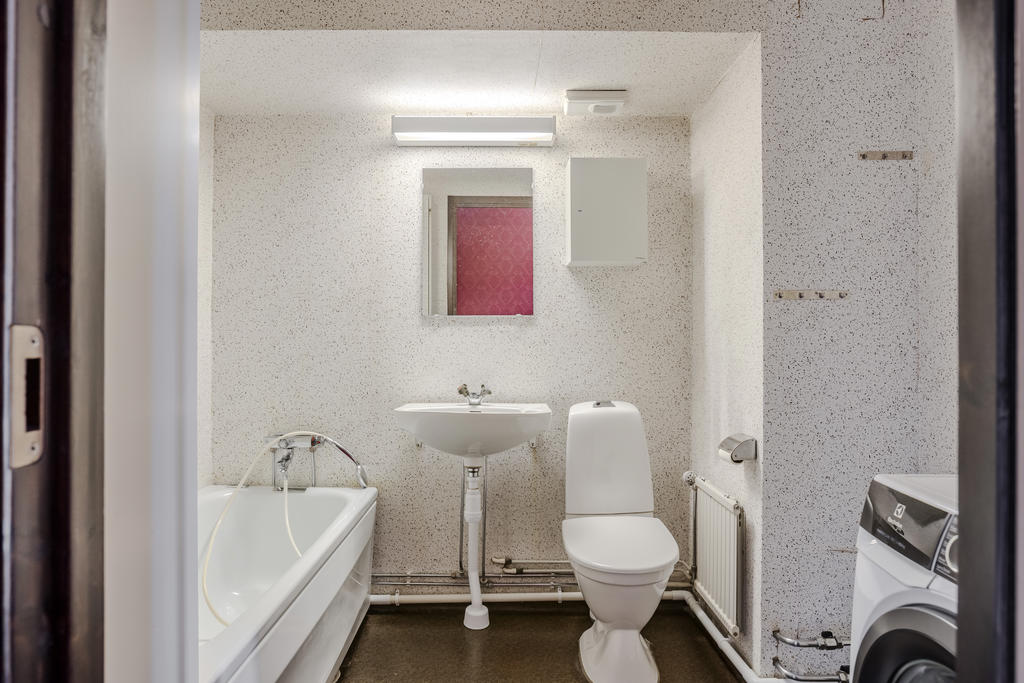 Badrum utrustat med wc handfat, badkar och tvättmaskin