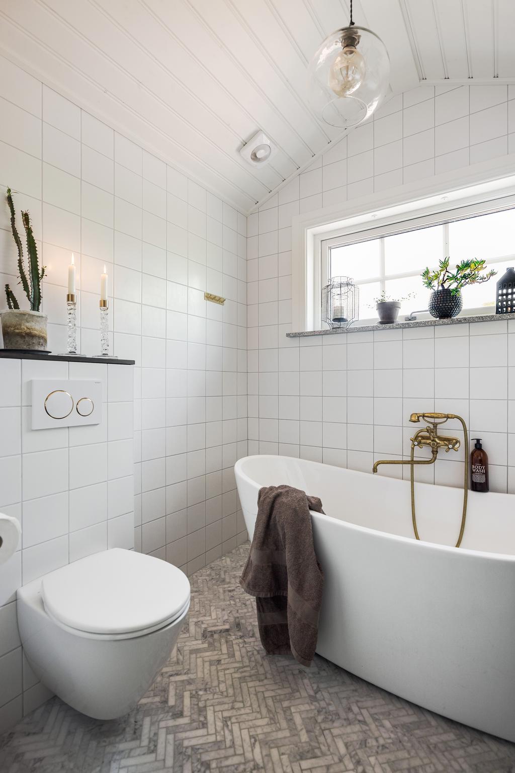 Badrummet på övre plan med fiskenbensmönstrat klinker och  badkar. 