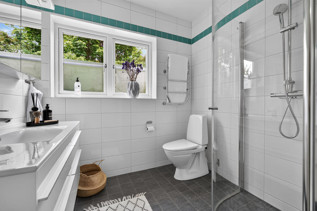 Badrum på entréplan utrustat med wc, handfat med kommod, dusch, handdukstork och golvvärme.