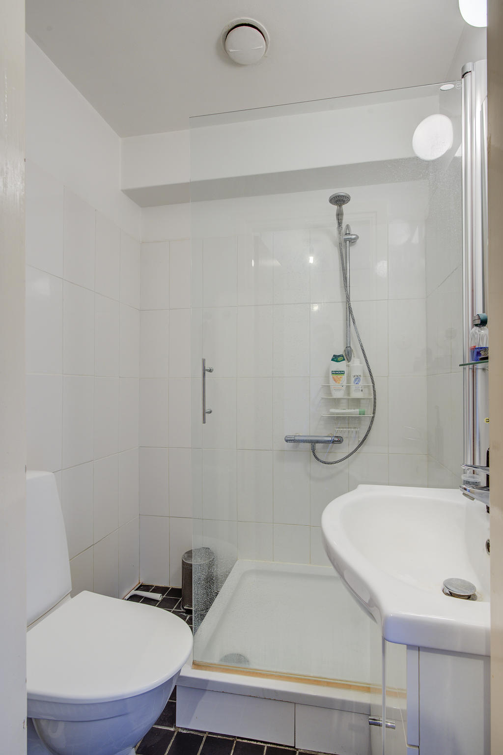 Badrum med toalett, handfat och duschkabin. Klinker på golv och kakel på väggar.