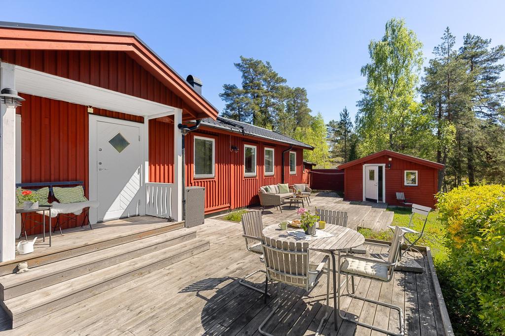 Solgassande uteplatser utmed husets framsida och gäststuga