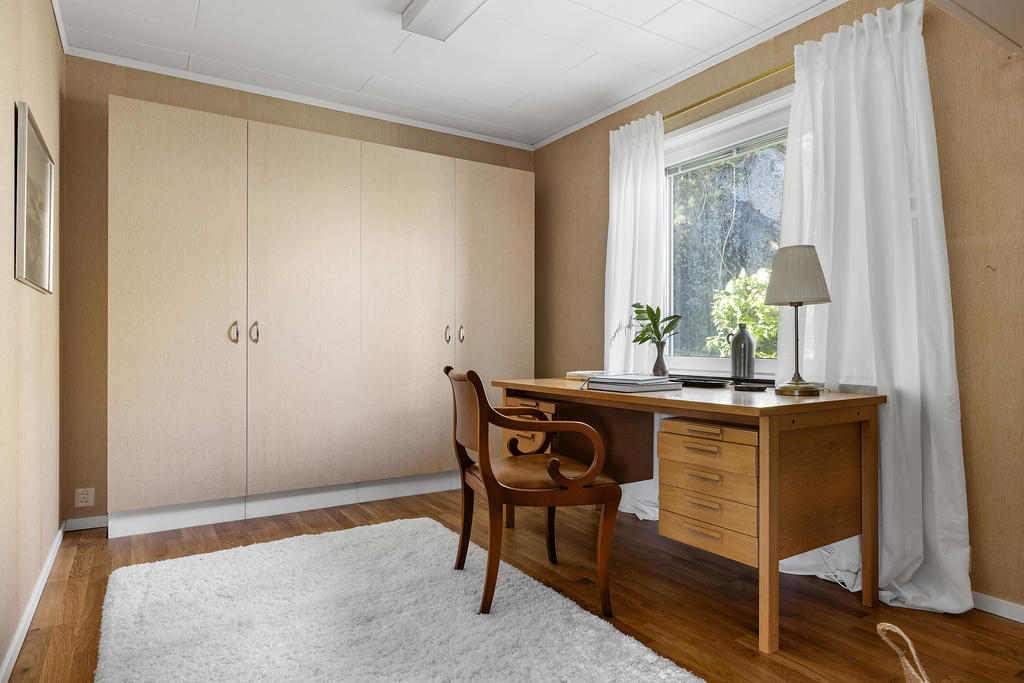 Sovrum 4 vid entrén med fyra fasta garderober. Utanför fönstren blommar vita syrener