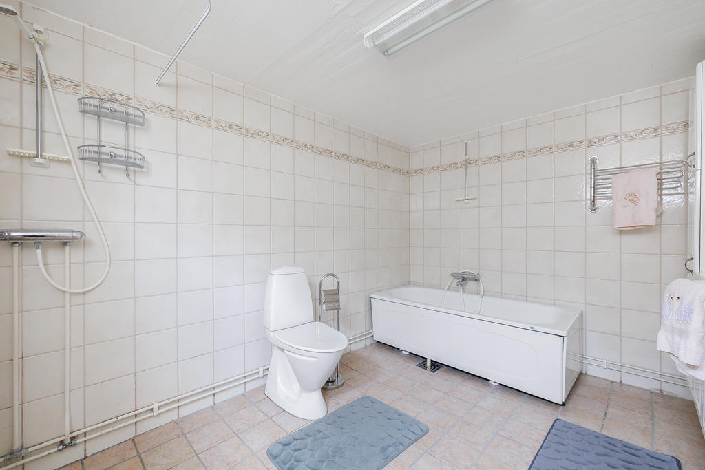 Helkaklat badrum utrustat med badkar, duschplats, kommod, spegelskåp samt wc