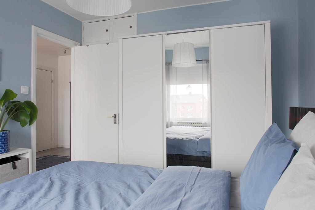 Ingång till sovrum och gott om förvaringsmöjligheter i inbyggda garderober bakom dörren och en lös garderob 