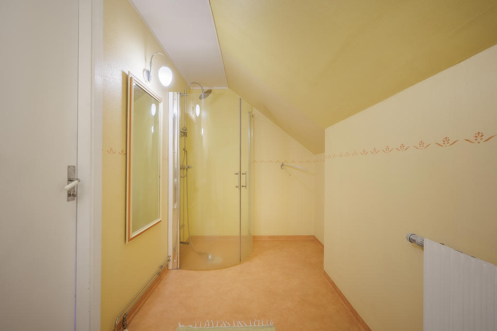Badrum utrustat med wc, handfat, spegelskåp, dusch och duschväggar. 