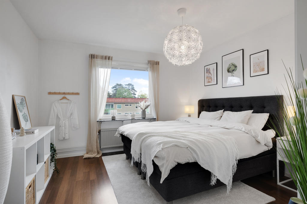 Sovrum med vita väggar och gott om plats för en dubbelsäng
