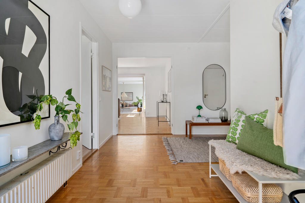 Välkomnande hall med goda avhängningsmöjligheter. Via garaget nås även bostadens praktiska groventré