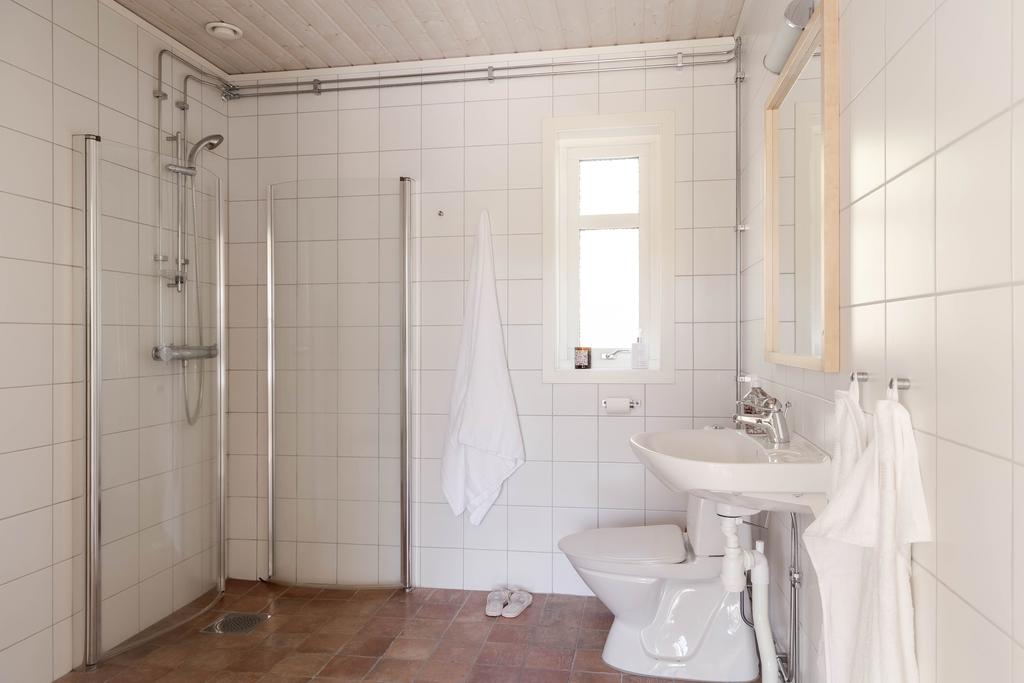 Ljust badrum med dusch, wc och handfat samt fönster som ger naturligt ljusinsläpp.