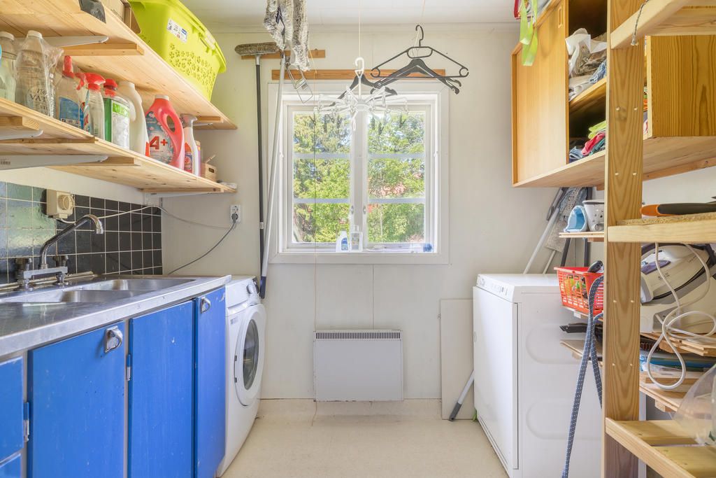 Tvättstuga med skåpsinredning och rostfri ho.
