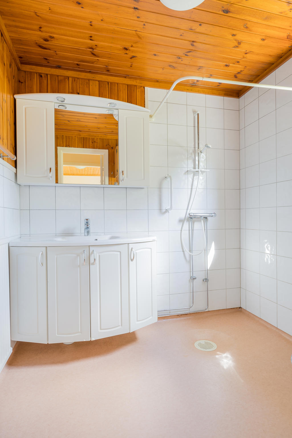 Badrum med plastmatta golv och kaklade väggar, utrustat med WC, handfat och kommod, spegelskåp samt duschplats