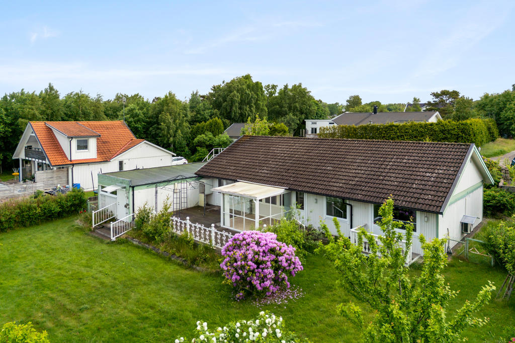 Huset ligger på en stor trädgårdstomt med altan, uterum och växthus. 