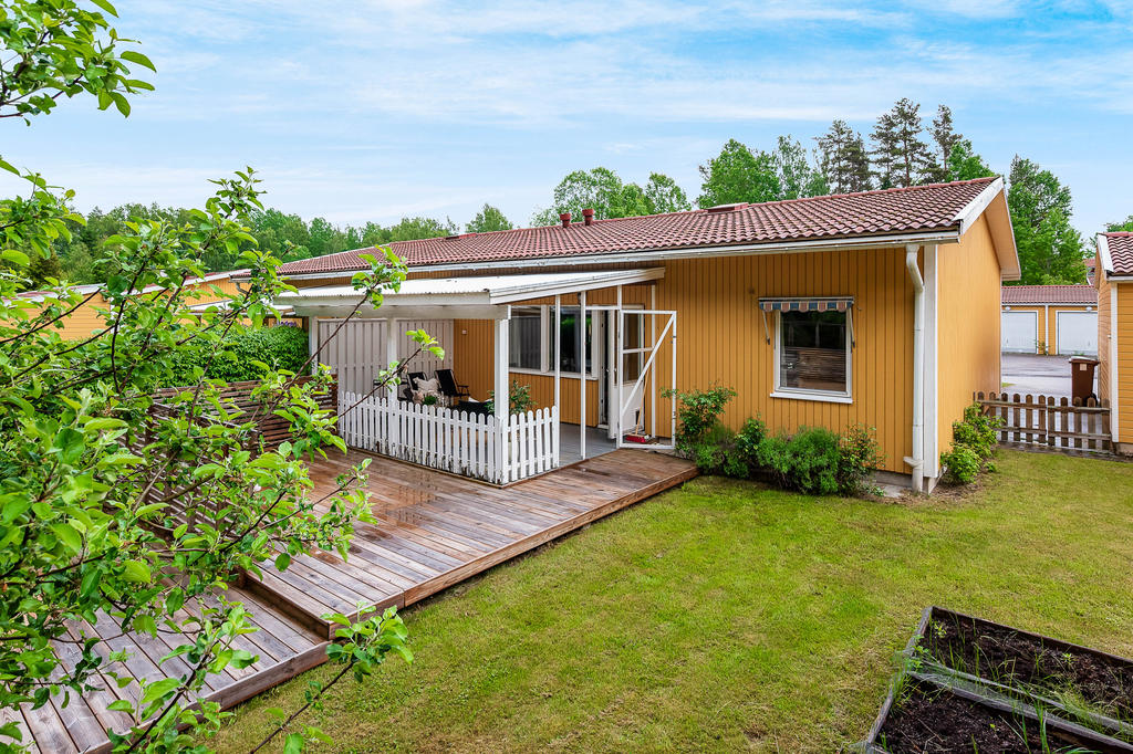 Baksidan med trädäck, gräsmatta och odlingslådor