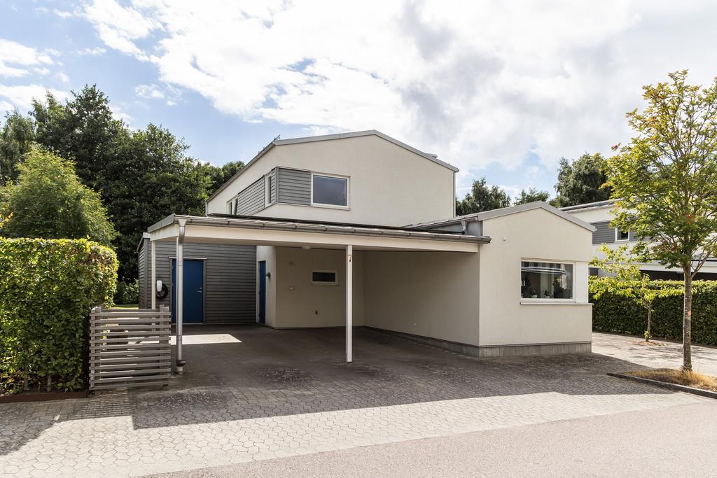 Framsidan erbjuder carport och en praktisk entré till huset.