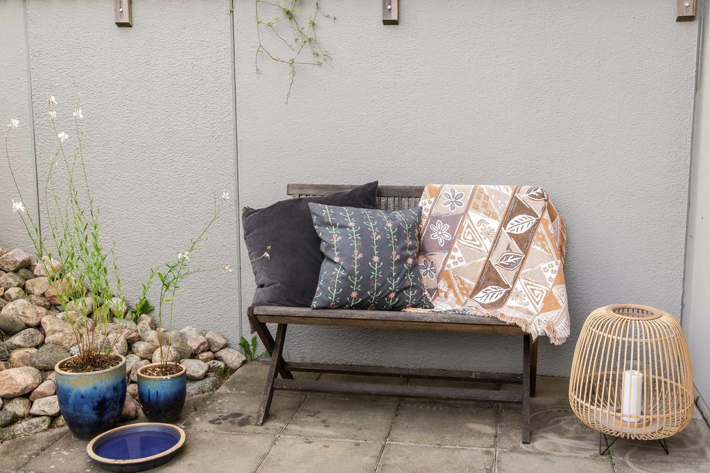 Mysig uteplats intill fasaden med sittbänk – en trevlig plats för avkoppling och en stund i solen.