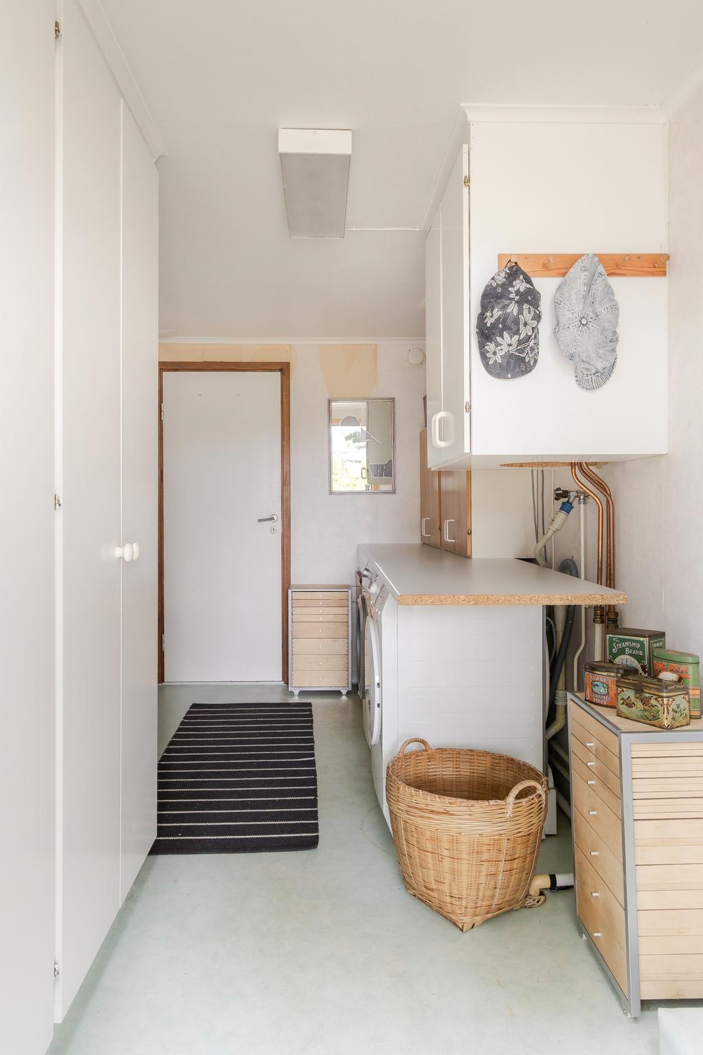 Praktisk tvättstuga med goda arbetsytor och plats för tvättmaskin samt övrig förvaring.